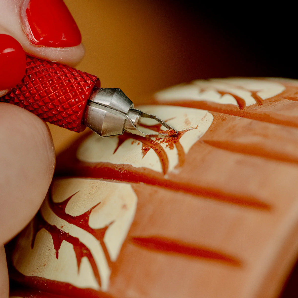 Carving a sgraffito pattern through pale slip to the red clay beneath with a BuschKraft Dragonfly tool