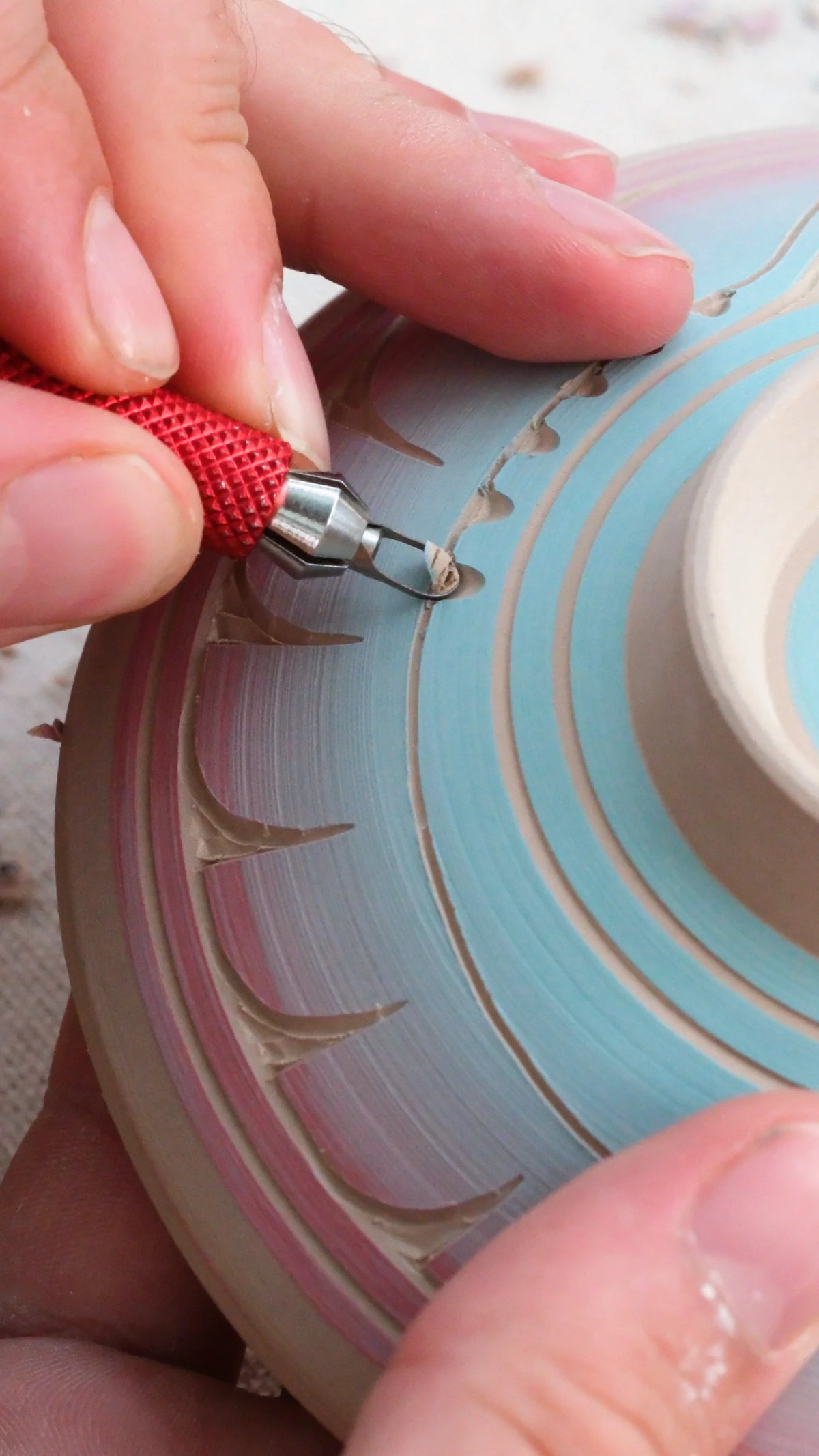 Carving curved leaf marks into a bowl covered in blue slip with a BuschKraft Dragonfly blade