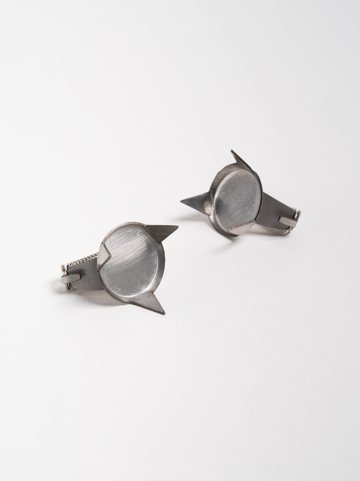 Side view of finger-mounted ceramic glaze dipping tools showing pointed grips and coiled springs.