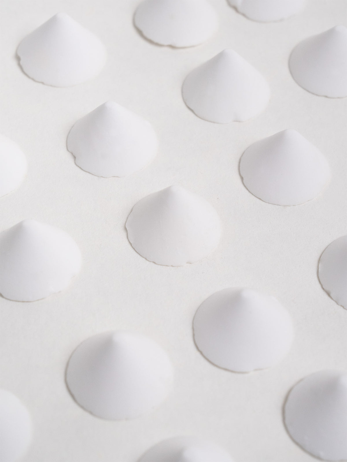 Twenty-five evenly spaced ceramic firing stilts displayed in rows, used to support glazed pieces in the kiln.