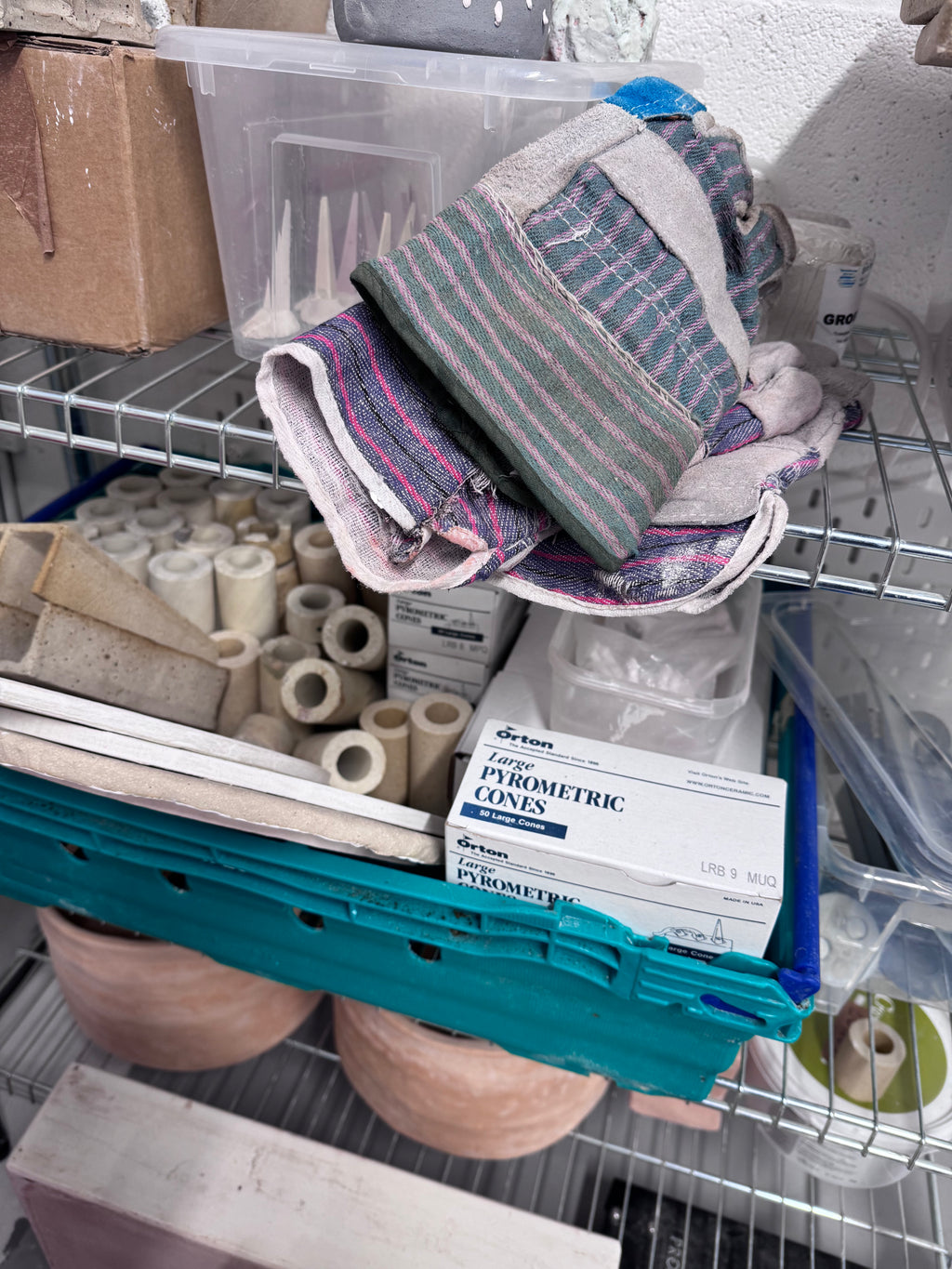 Heat-resistant kiln gloves beside pyrometric cones on a work surface.