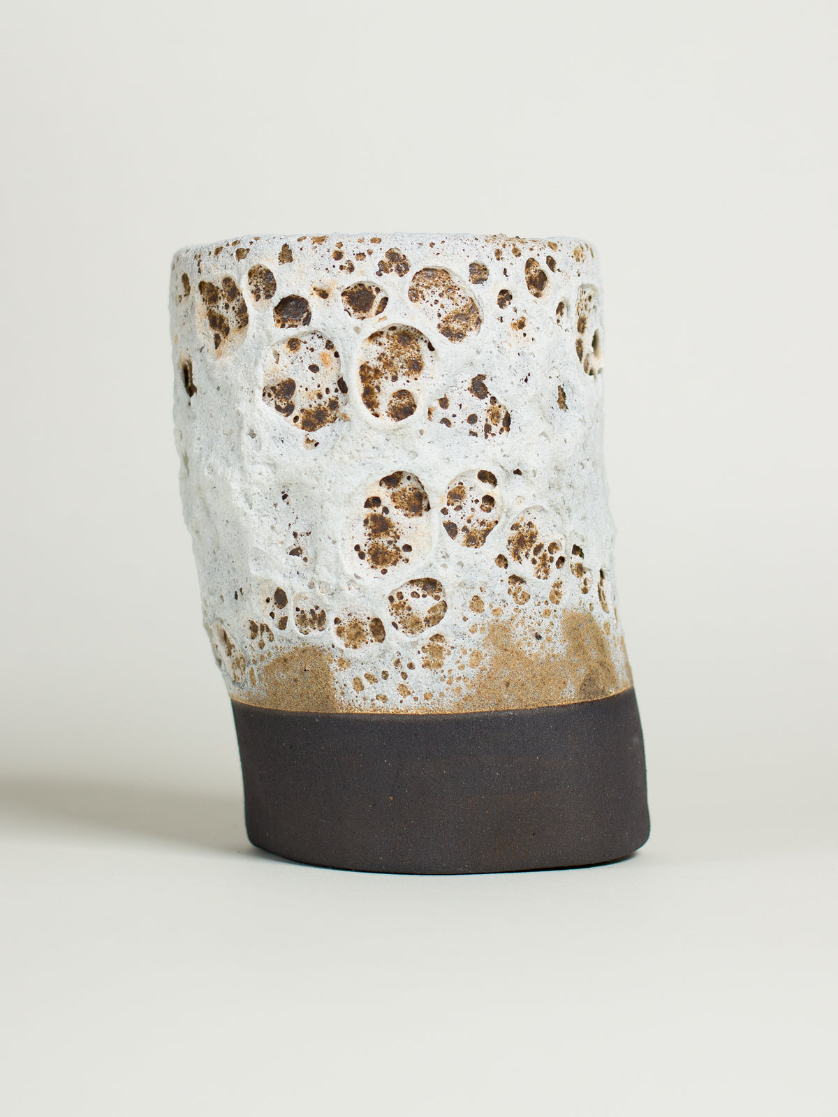 A ceramic piece with a textured white surface and dark base, reminiscent of volcanic lava.