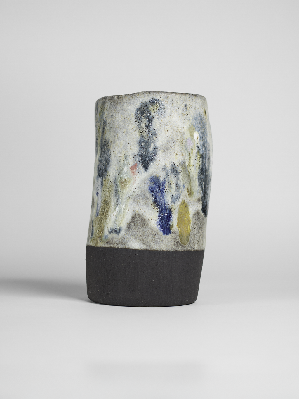 A ceramic mug with a speckled, textured glaze featuring various colors including blue, gray, and yellow.
