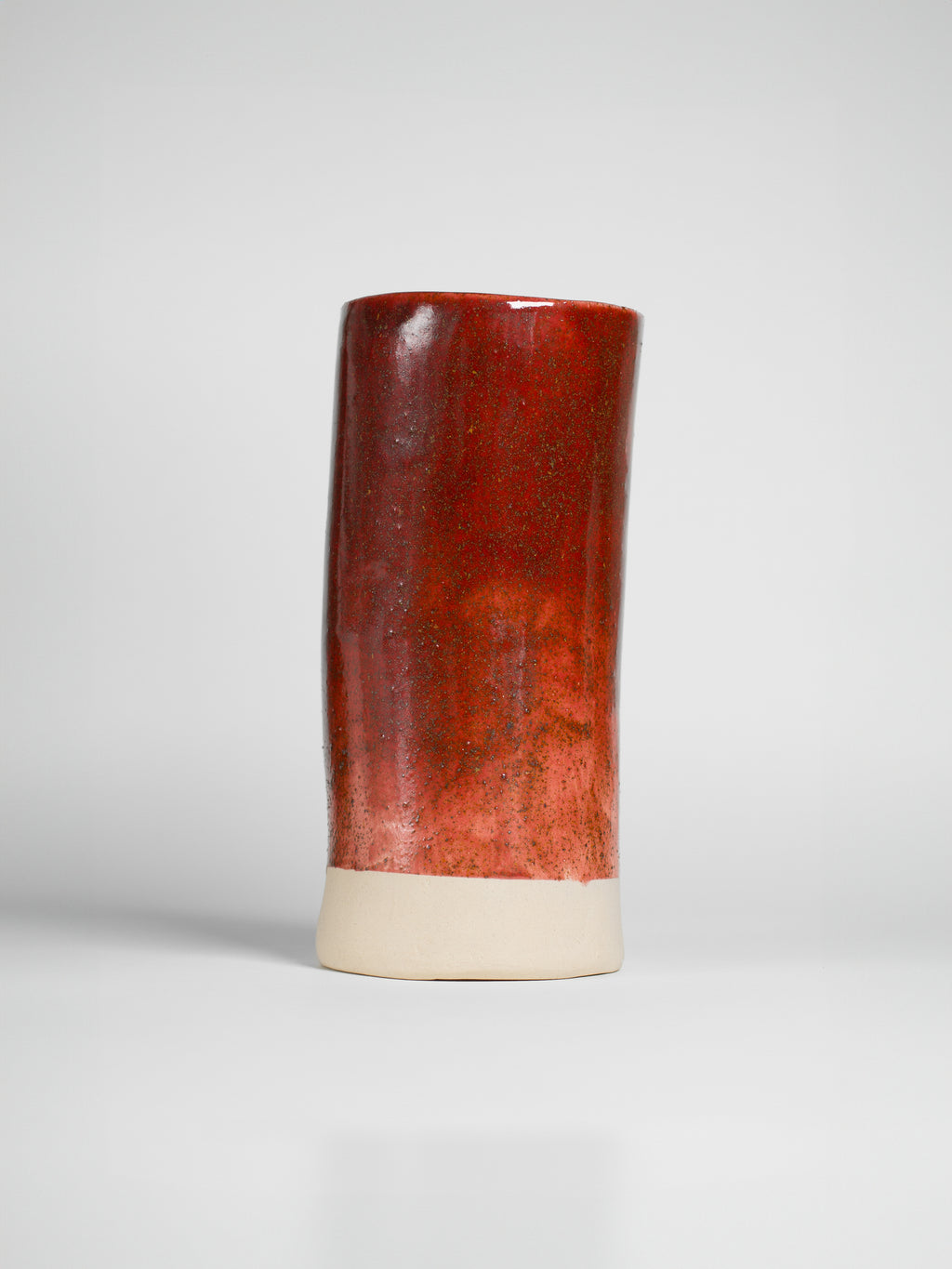 Cranberry Red on a tall thrown cylinder, glossy red deepening to oxblood at the rim over a pale clay foot