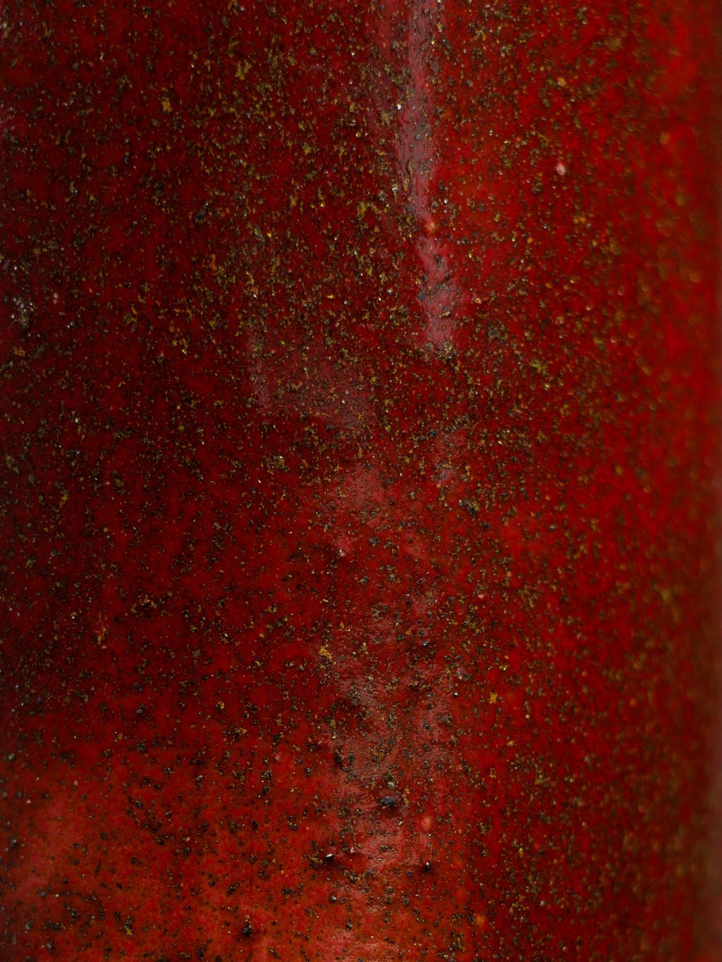 Close view of the Cranberry Red surface, dark speckle scattered through a glossy red ground