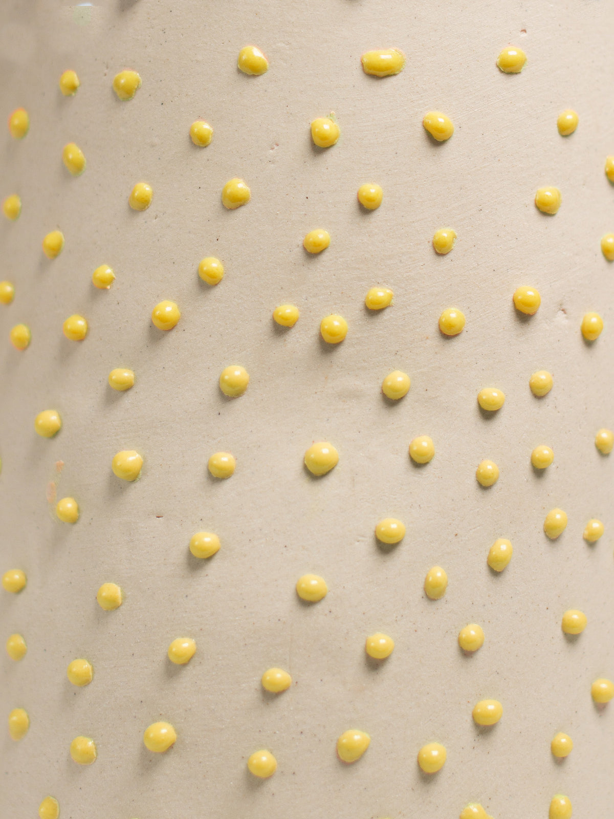 Close up of Yellow Liquid Gloop, raised yellow droplets across a cream surface