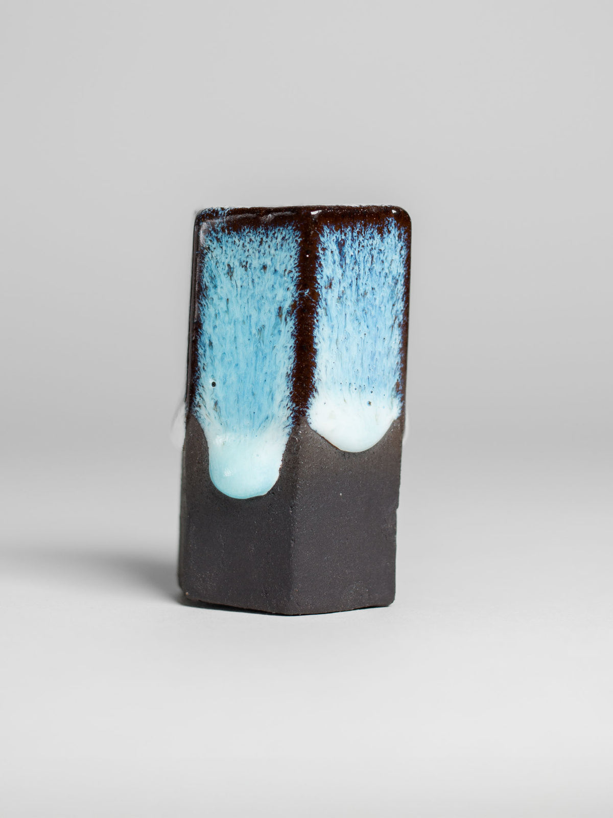 Shiny white Snow Drift glaze applied on black stoneware, showcasing its drippy texture and captivating variations.