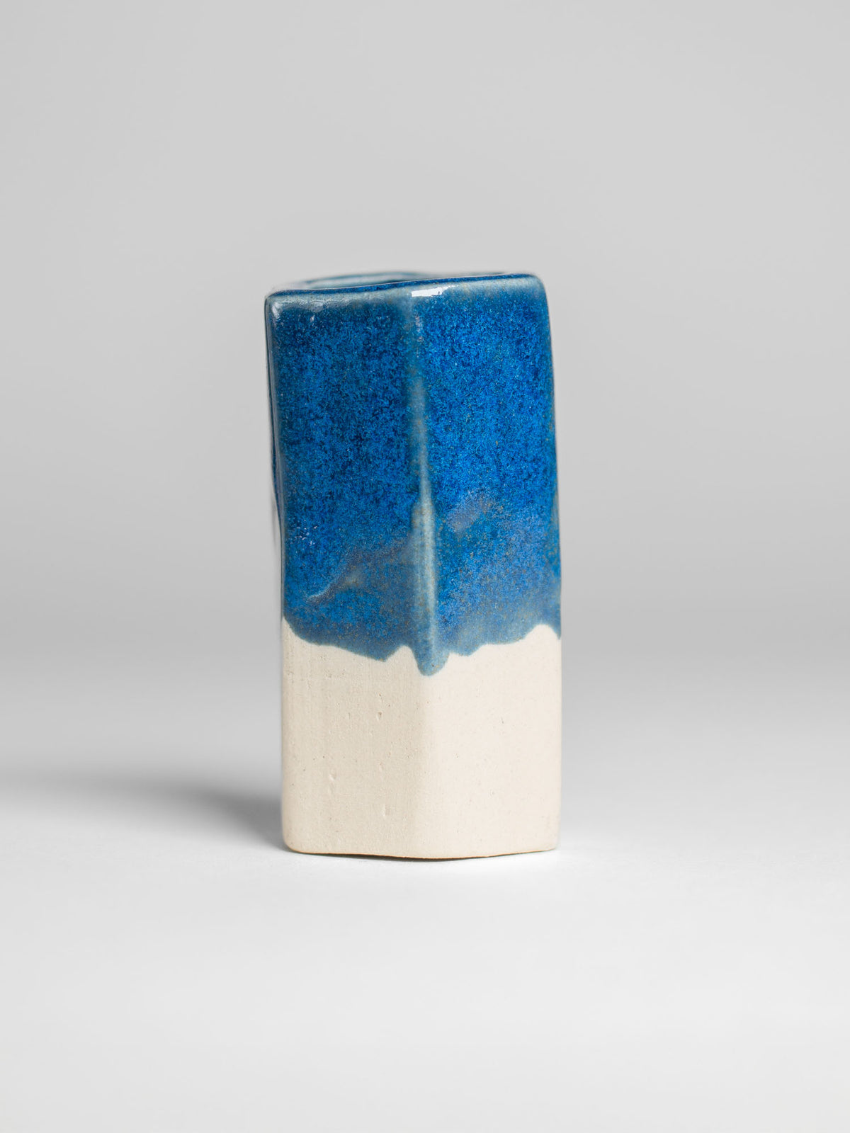A handmade ceramic object with a tall, cylindrical shape. The upper portion is glazed in shiny micro crystalline sky blue pottery glaze