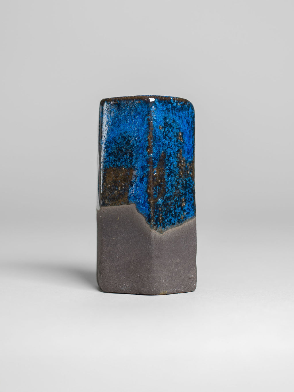 Frosty Blue test tile on dark clay, bright blue broken by brown where the body shows through