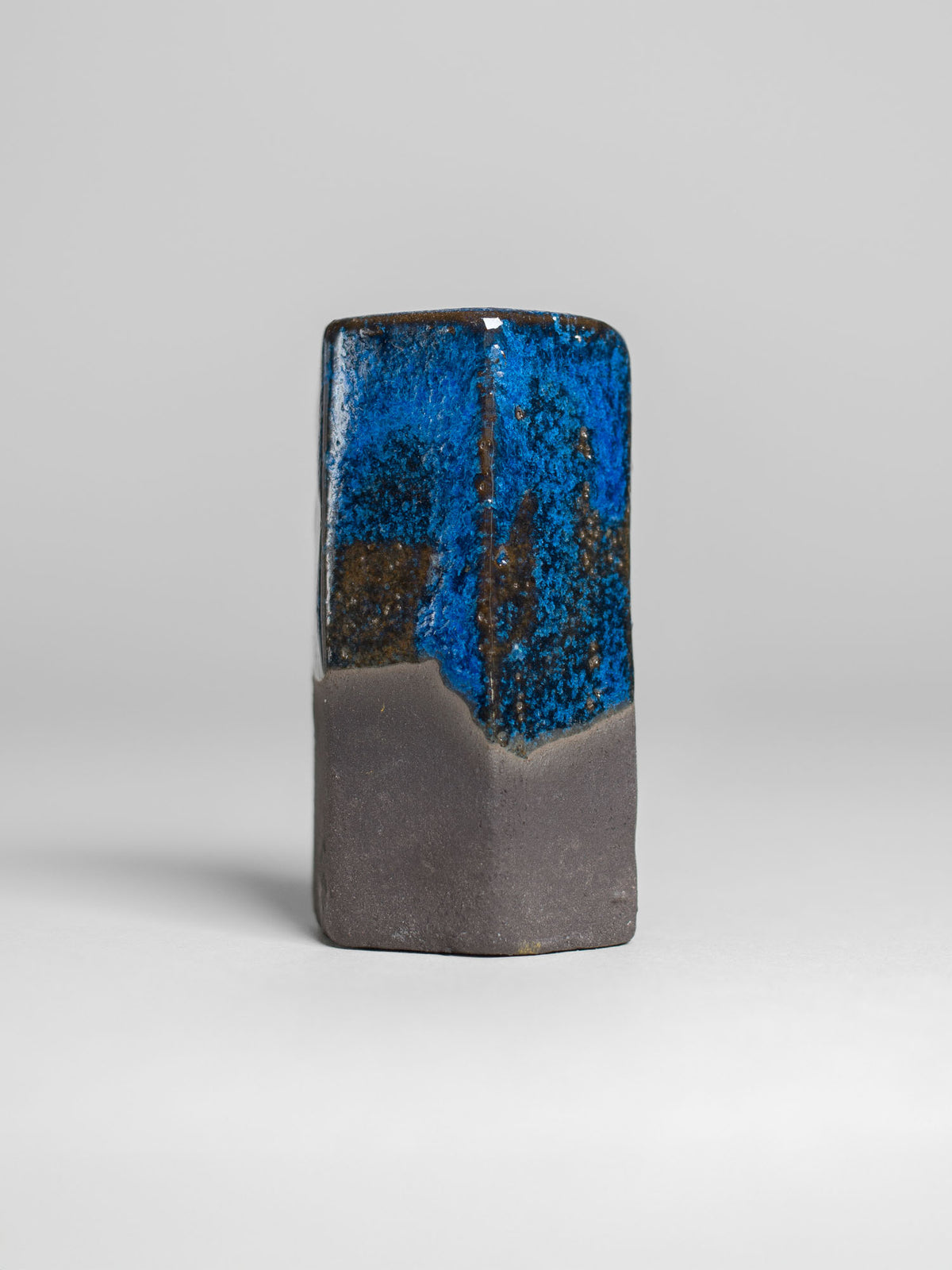 A handmade ceramic object with a tall, cylindrical shape. The upper portion is glazed in shiny micro crystalline sky blue pottery glaze