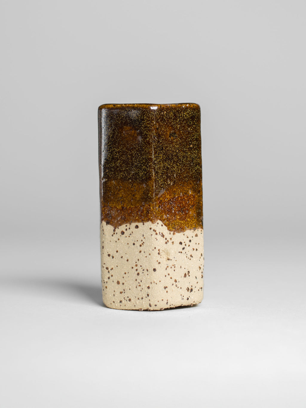 Golden Honey test tile on speckled clay, gold-flecked brown pooling to clear amber where it thickens