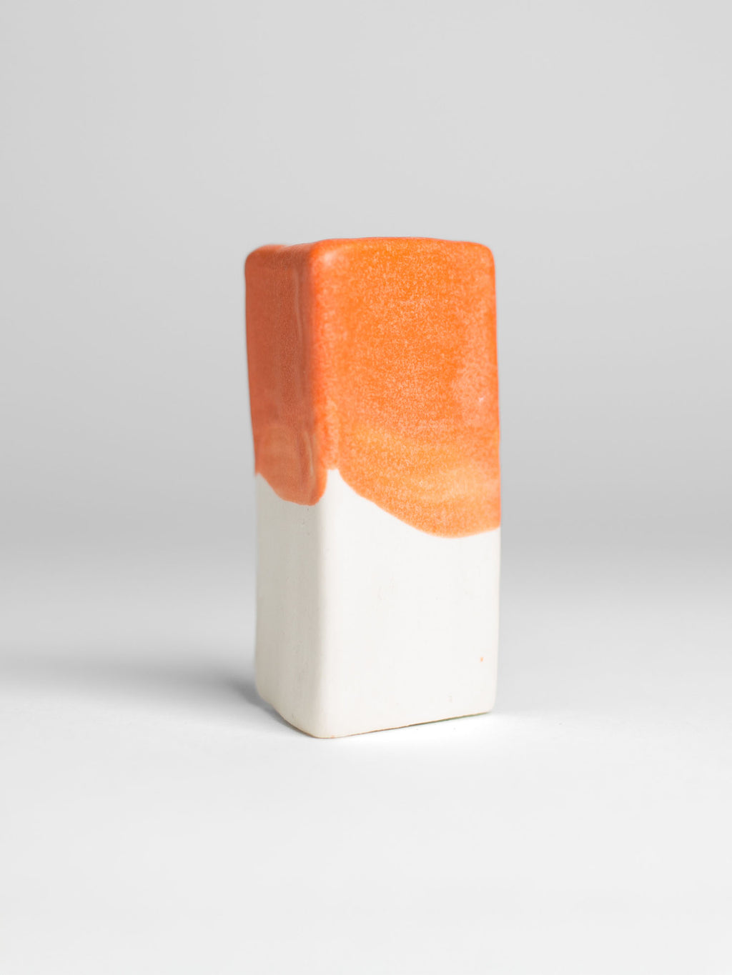 Orange Pastel Dreams test tile on porcelain, orange breaking paler at the thin edge of the glaze