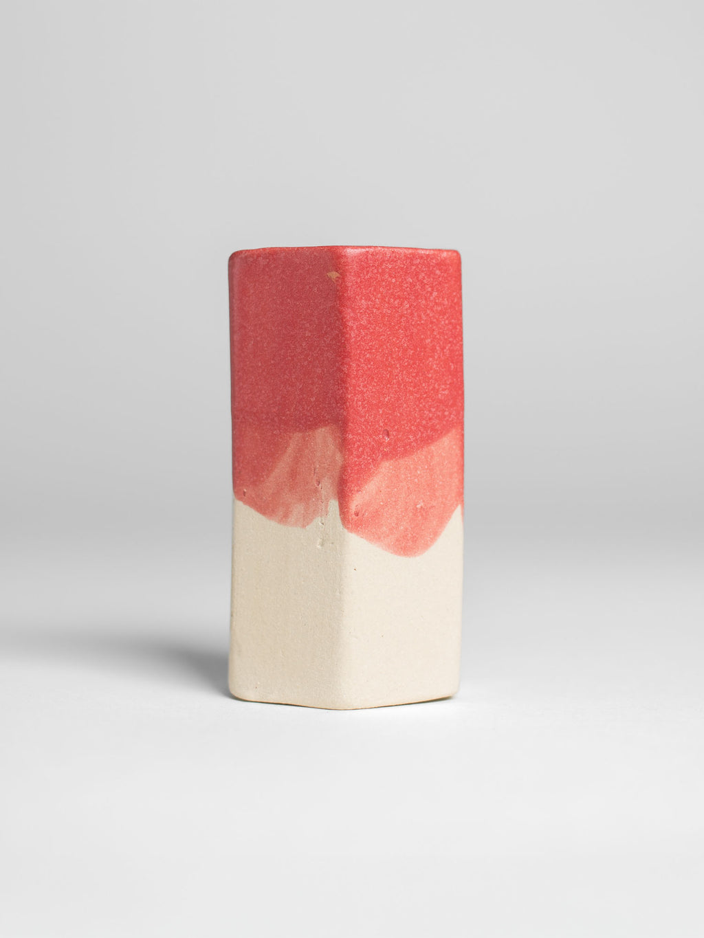 Hot Red Pastel Dreams test tile on pale clay, coral red breaking lighter where the coat runs thin