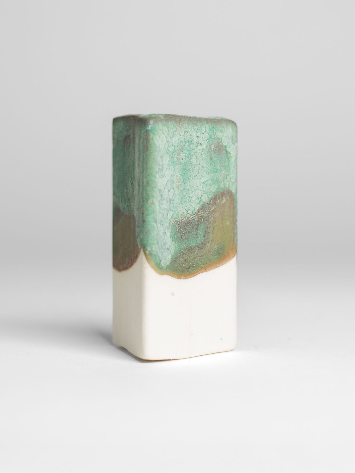 Malachite Green test tile on white clay, green pooling to ochre at the glaze line
