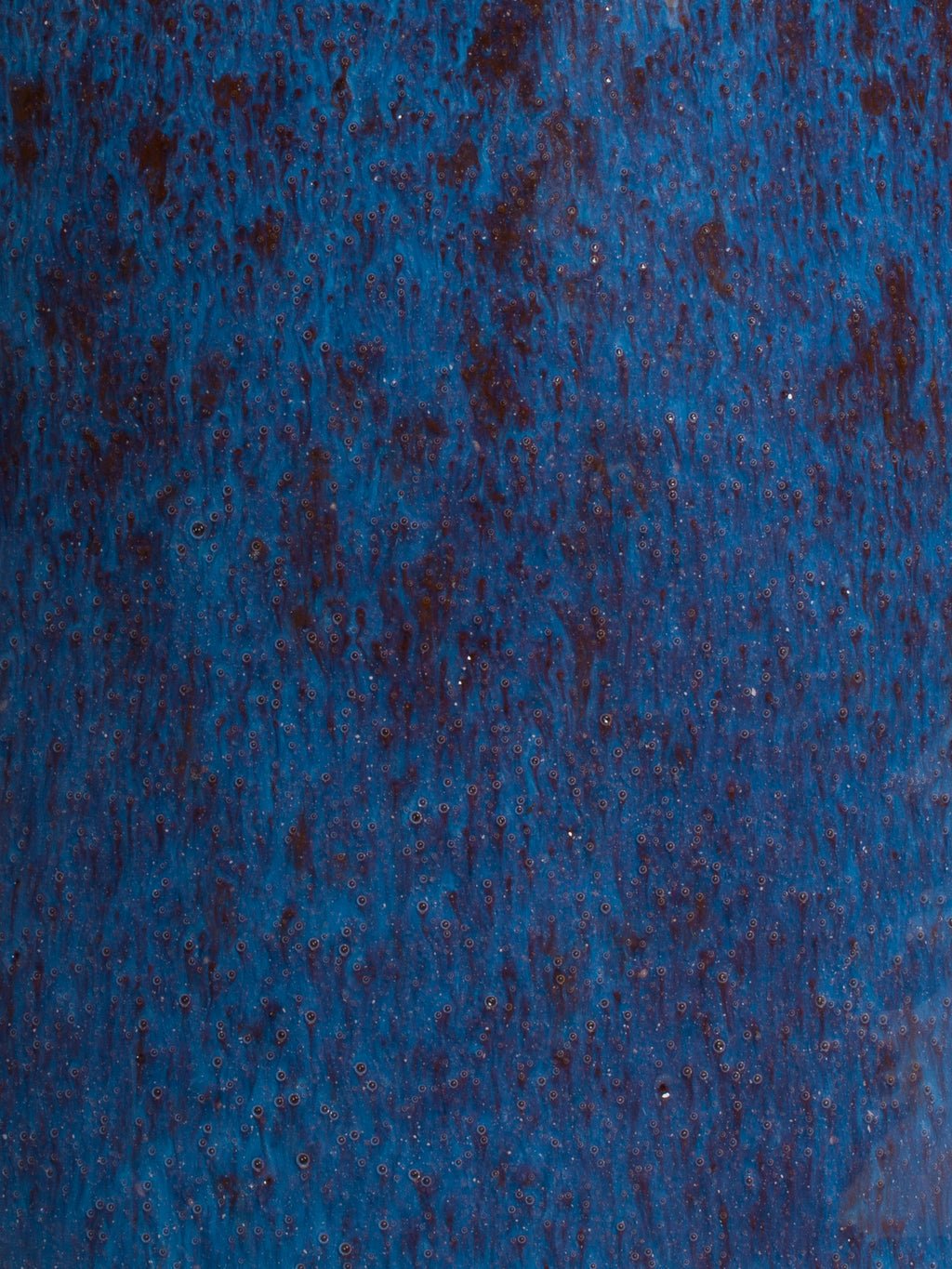 Close-up of Snow Drift brush-on glaze with shiny white rivulets, enhancing textured designs on ceramic surfaces.
