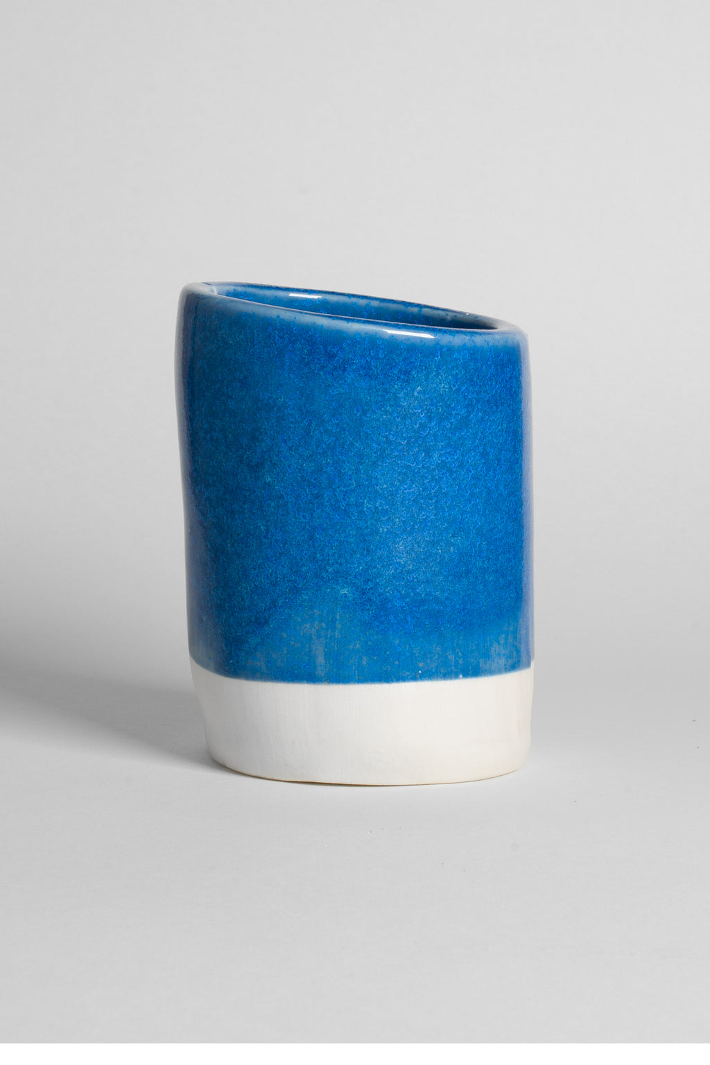 Frosty Blue on a thrown cup of white clay, even glossy mid-blue with a crisp line above the raw foot