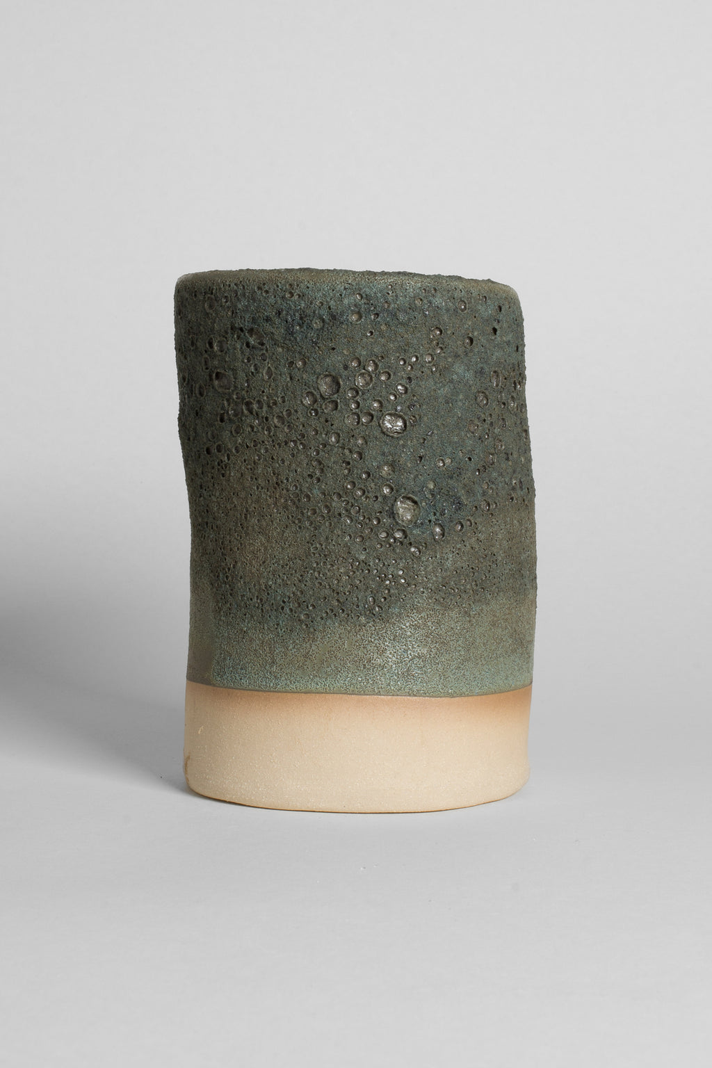 Lichen Grey on a thrown cylinder, dry grey-green crater texture over a raw buff clay foot
