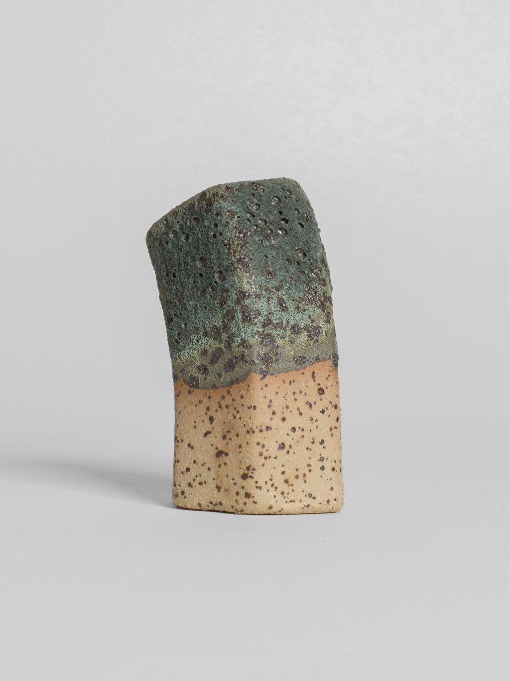 Lichen Grey test tile on speckled clay, cratered green-grey breaking thin at the glaze line