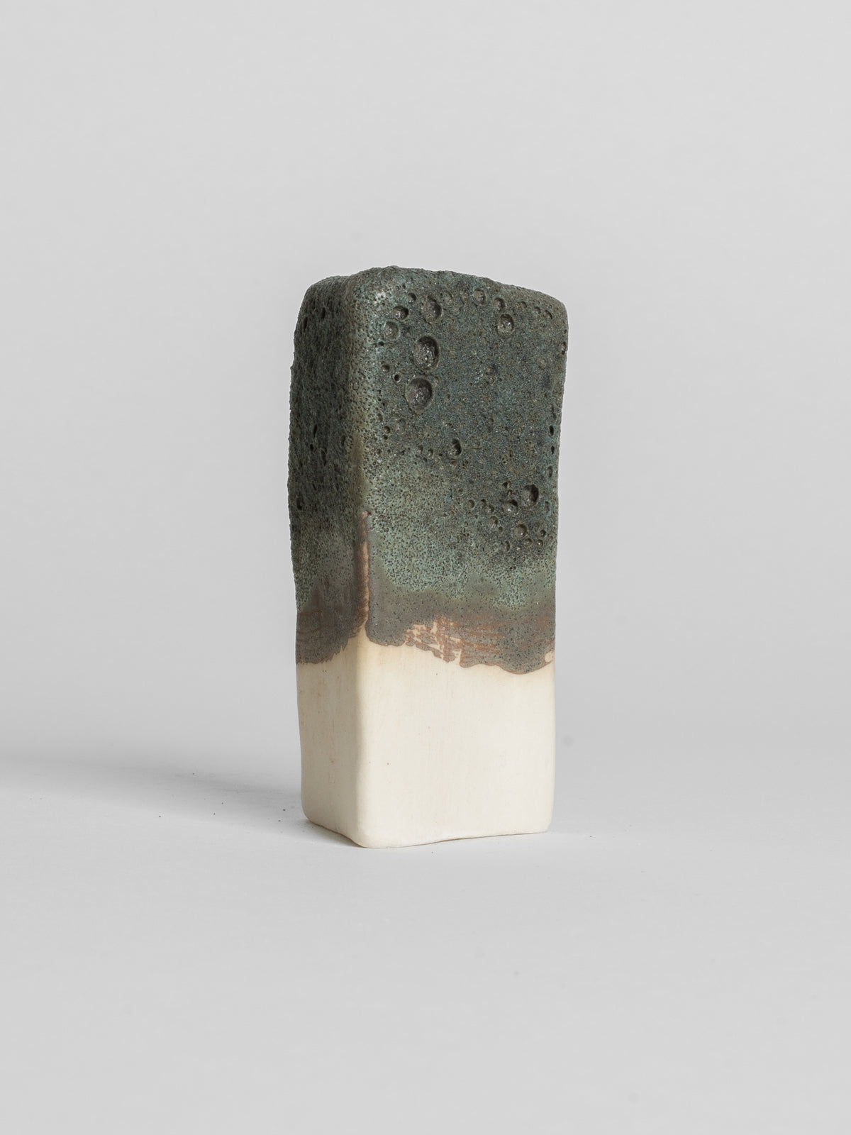 Lichen Grey test tile on white clay, deep crater texture over a bronze-brown glaze line