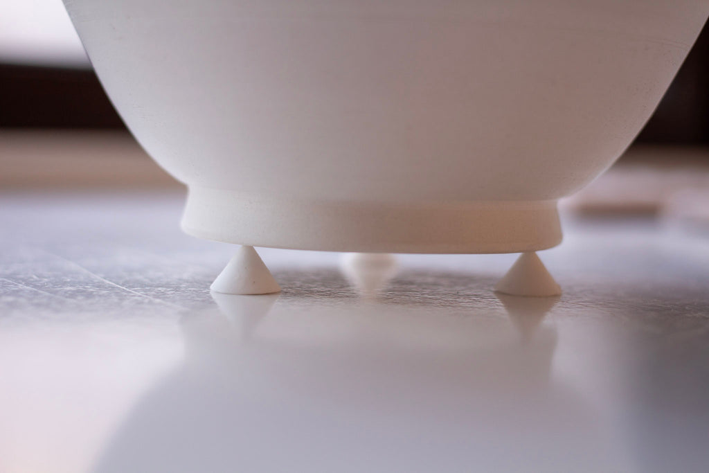Minimalist photograph of white ceramic stilts, cone-shaped and positioned in a perfect square formation.