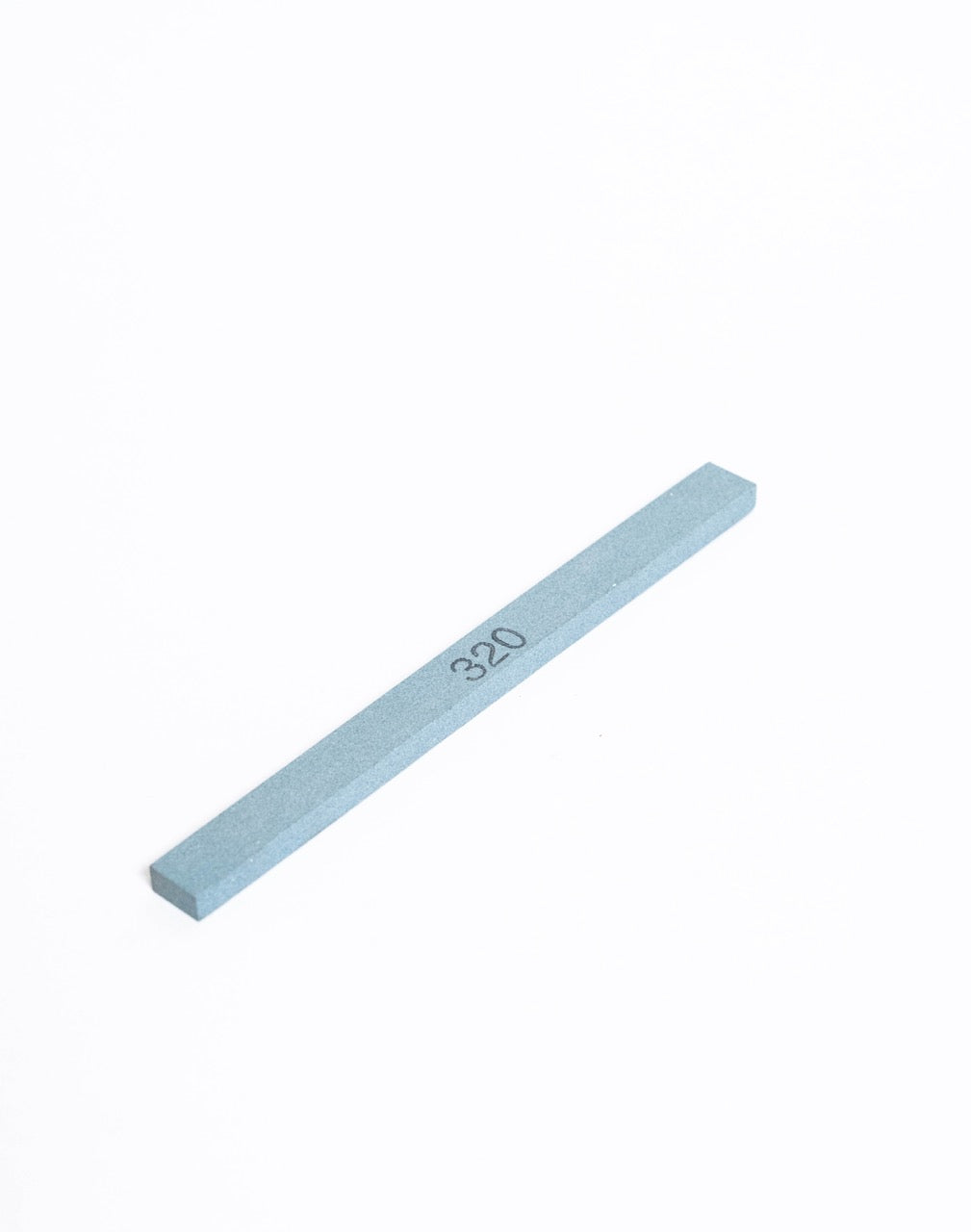 The whetstone stick at an angle, showing the bevel along its long edge.