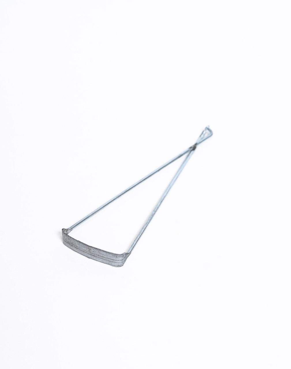Bicycle trimming tool laid flat at an angle, showing the curved blade and twisted wire handle