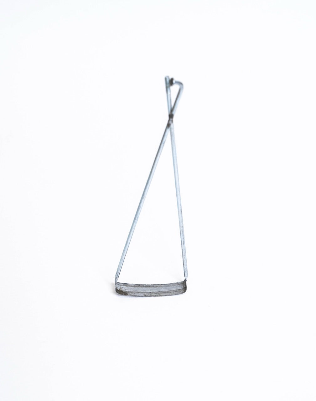 Bicycle trimming tool stood upright, curved cutting blade along the base of the triangle