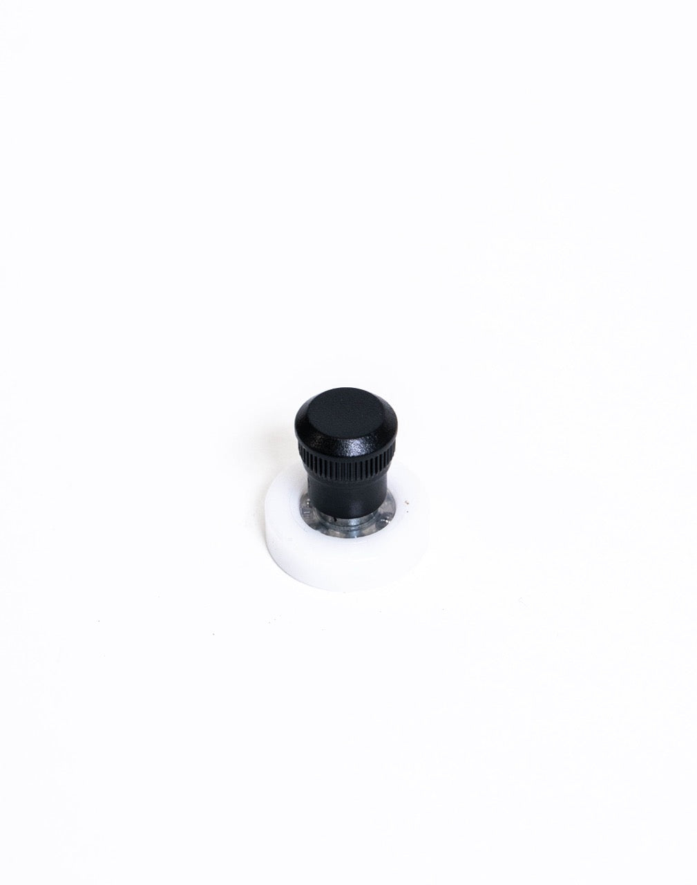 Black knurled spinner knob on a white nylon disc base, seen from the front