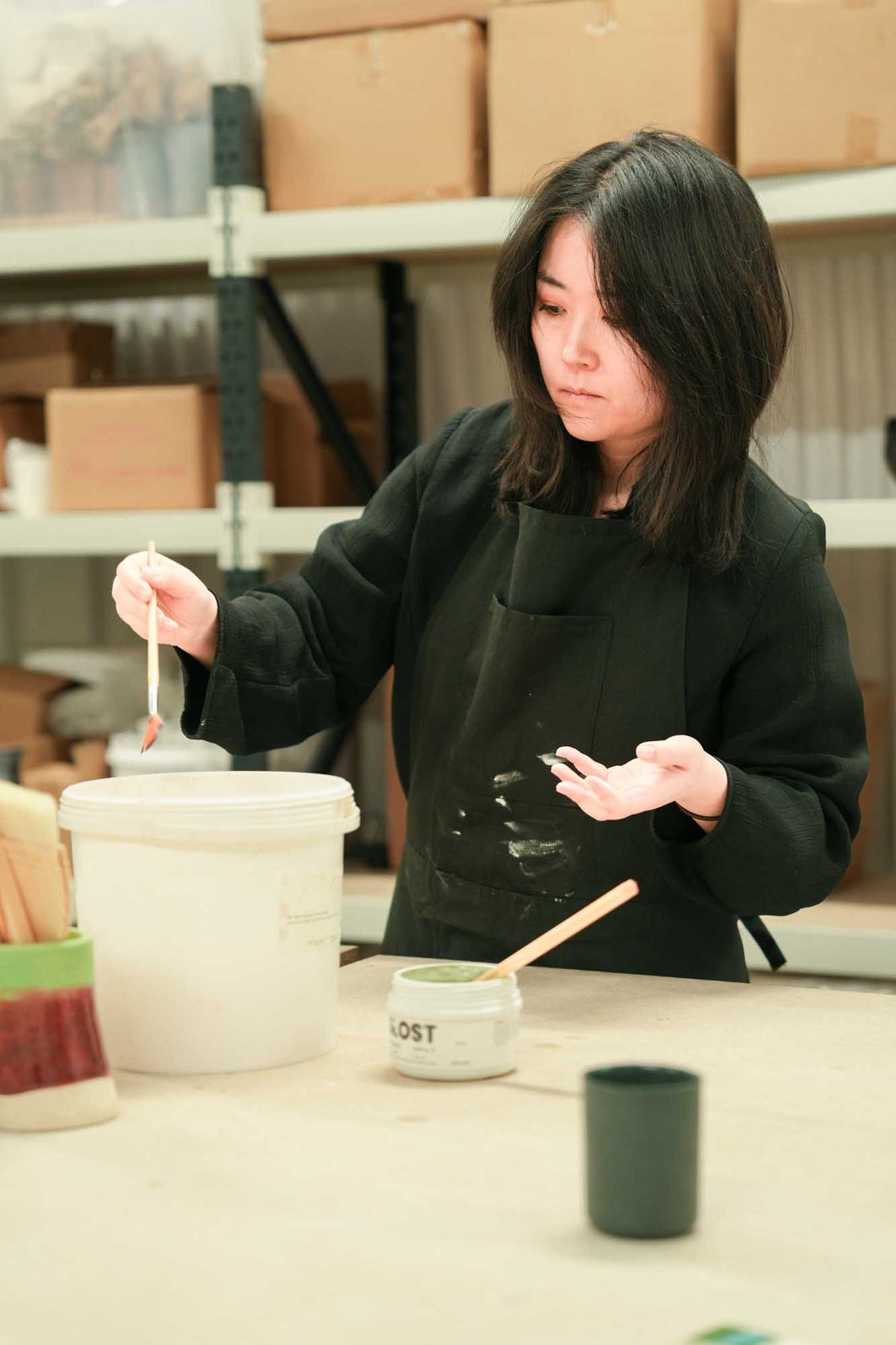 Person working with glaze in a pottery studio