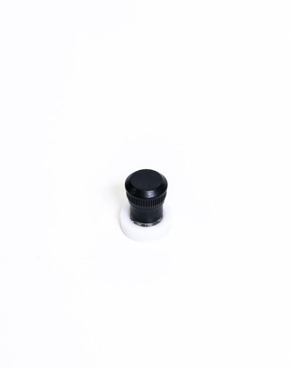 Black knurled spinner knob on a white nylon disc, close view of the knurled grip
