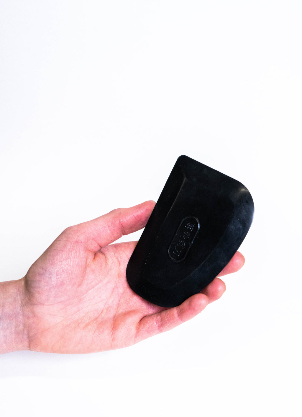 Hand holding the black rubber rib, showing its size against the fingers