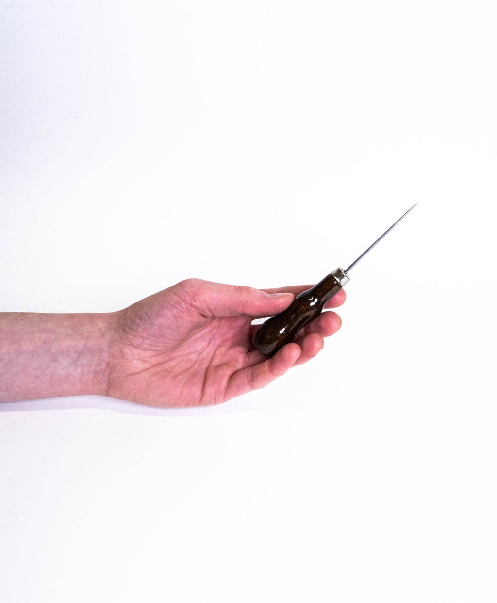 A hand holding a pin tool with a dark curved wooden handle