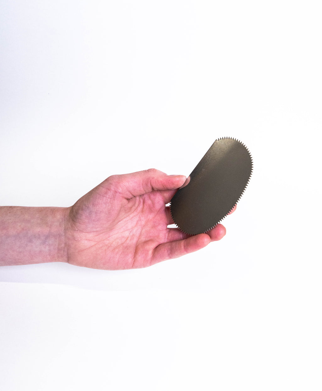 Hand holding the serrated oval steel rib, showing its size against the fingers