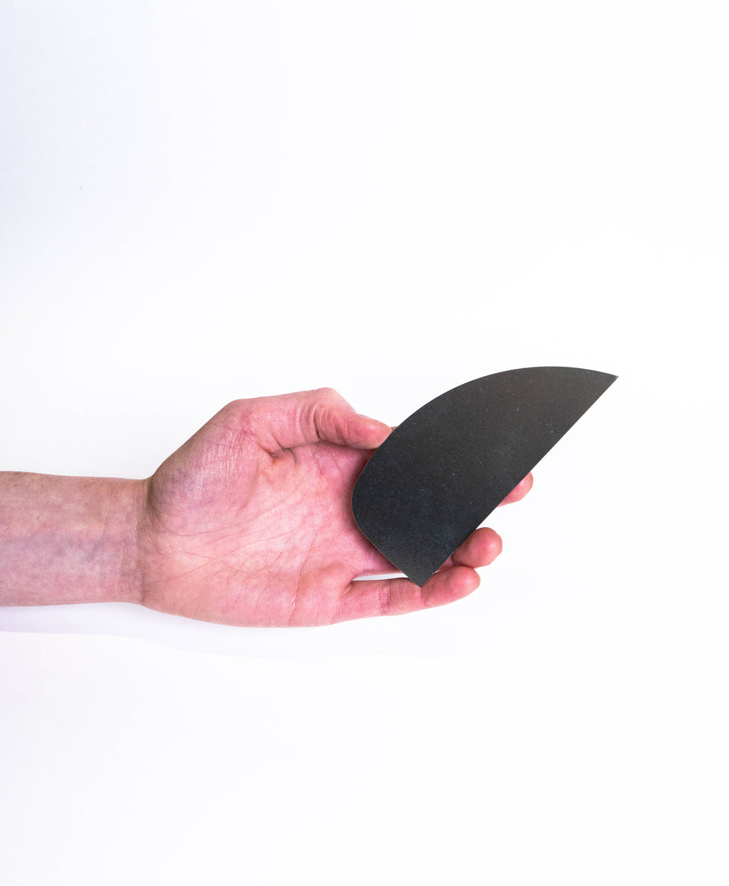 Hand holding a large matte black half moon rib, curved edge sweeping to a point