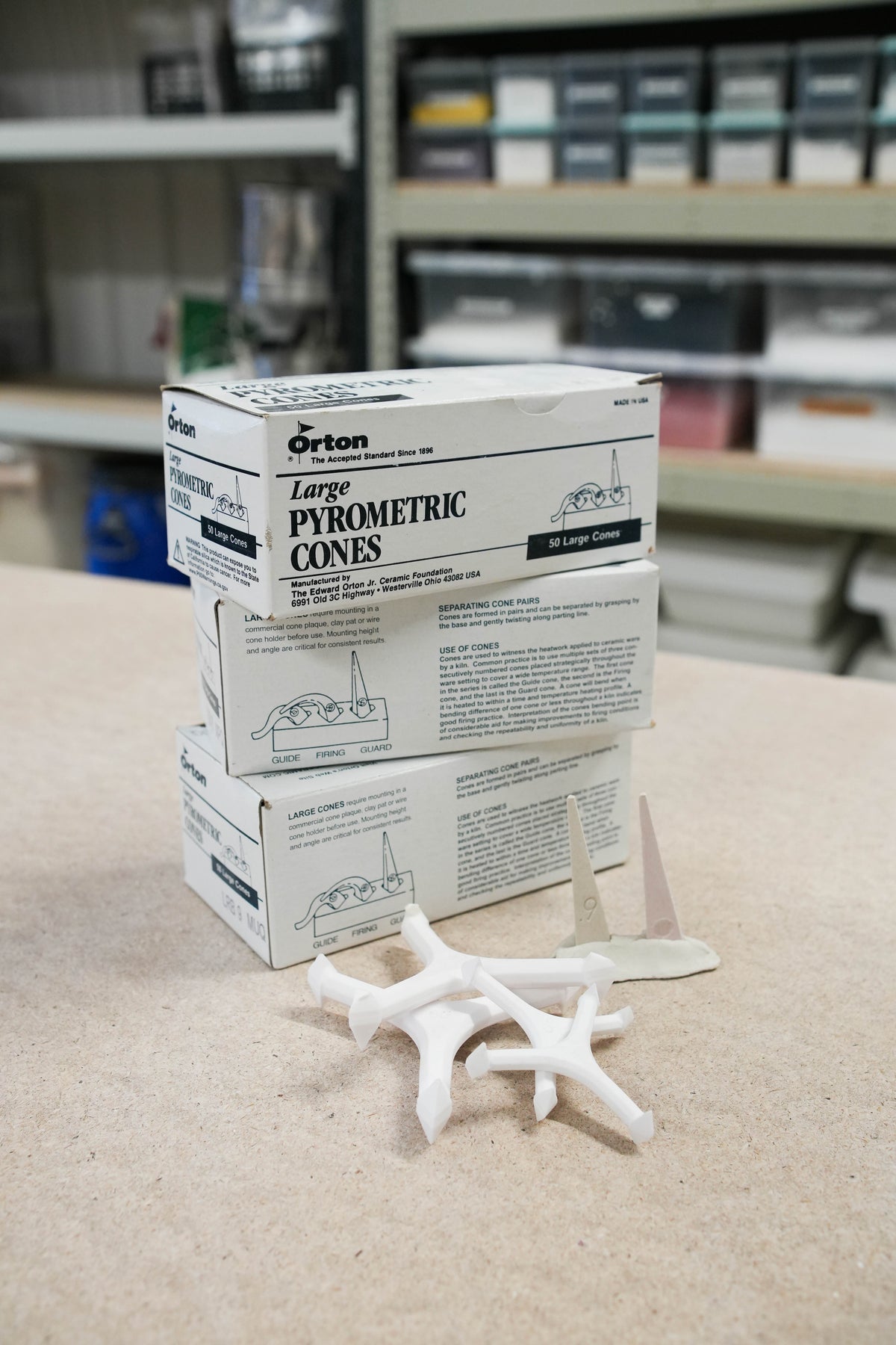Stacked boxes of Orton pyrometric cones on a table against a softly blurred background.