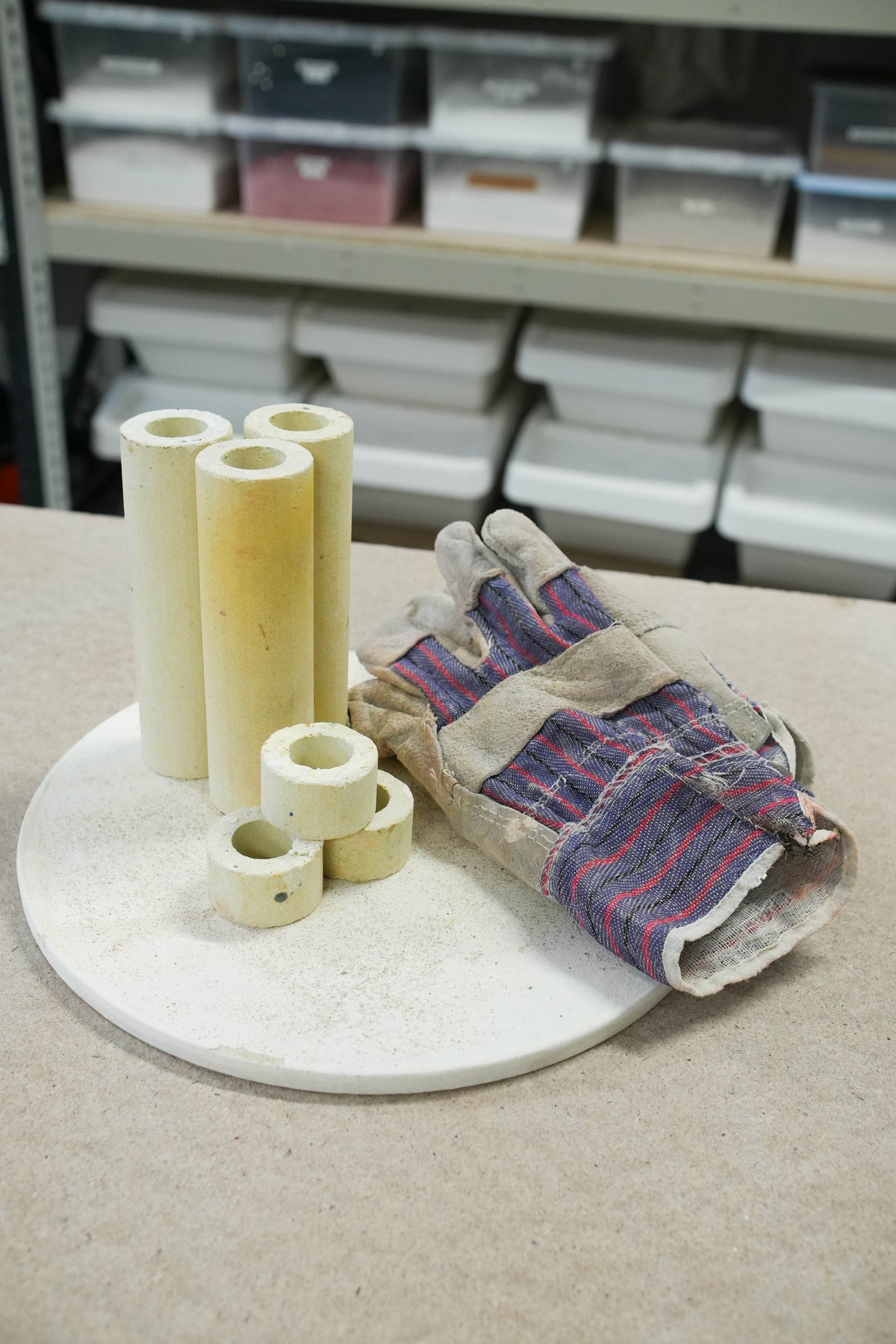 Kiln gloves, firing stilts and a kiln shelf laid out on a table.