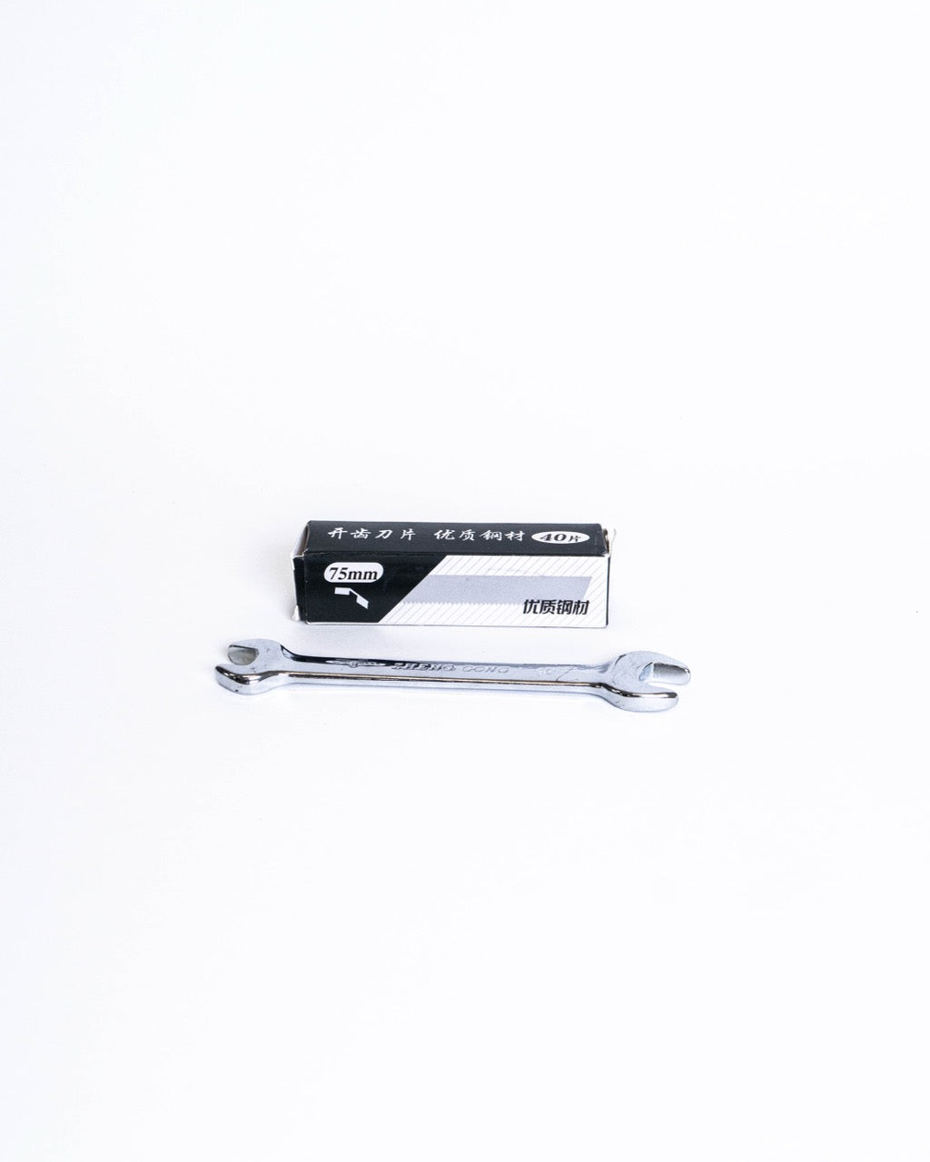 Box of 75mm replacement blades beside the spanner, on white