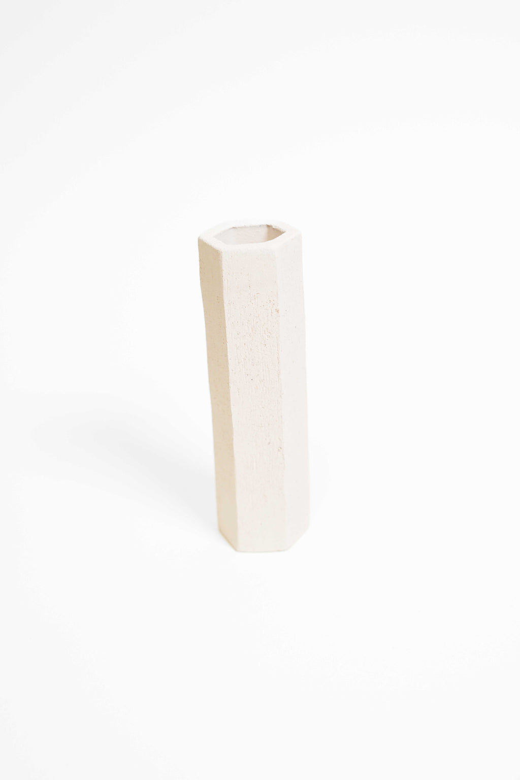 A tall faceted vessel thrown in ES109, unglazed and fired to a soft off-white
