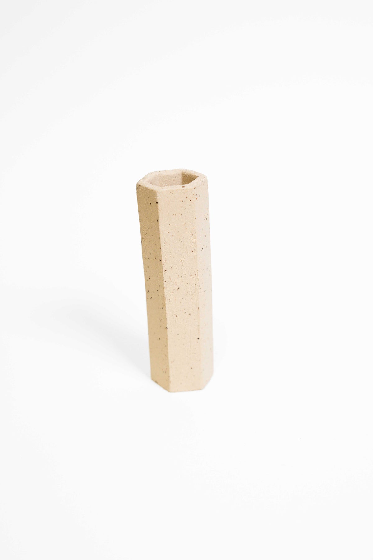 A tall faceted vessel in ES109 fired higher, warm buff with dark iron speckle