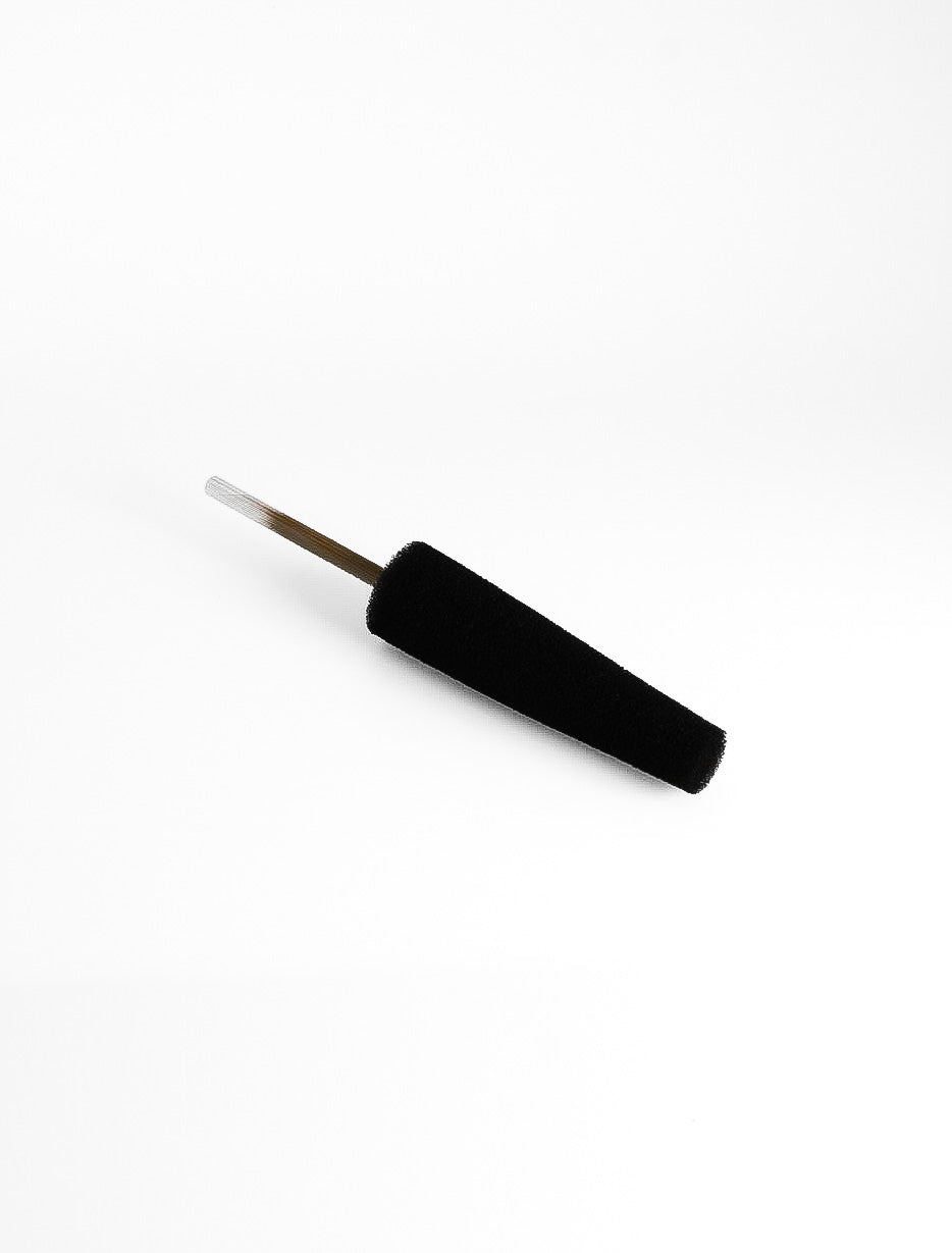 Close view of the black sponge on a stick, the dense foam head angled across a white background.
