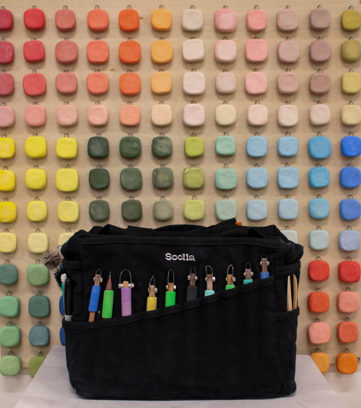 Black bag with colorful hooks on a wooden pegboard background